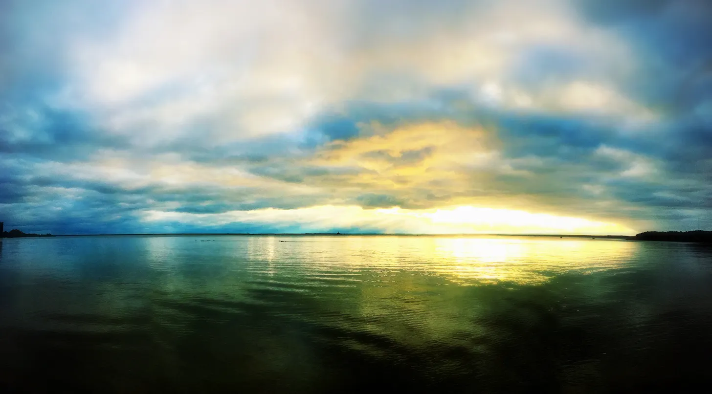 Wide still water under a sky that is just beginning to clear.