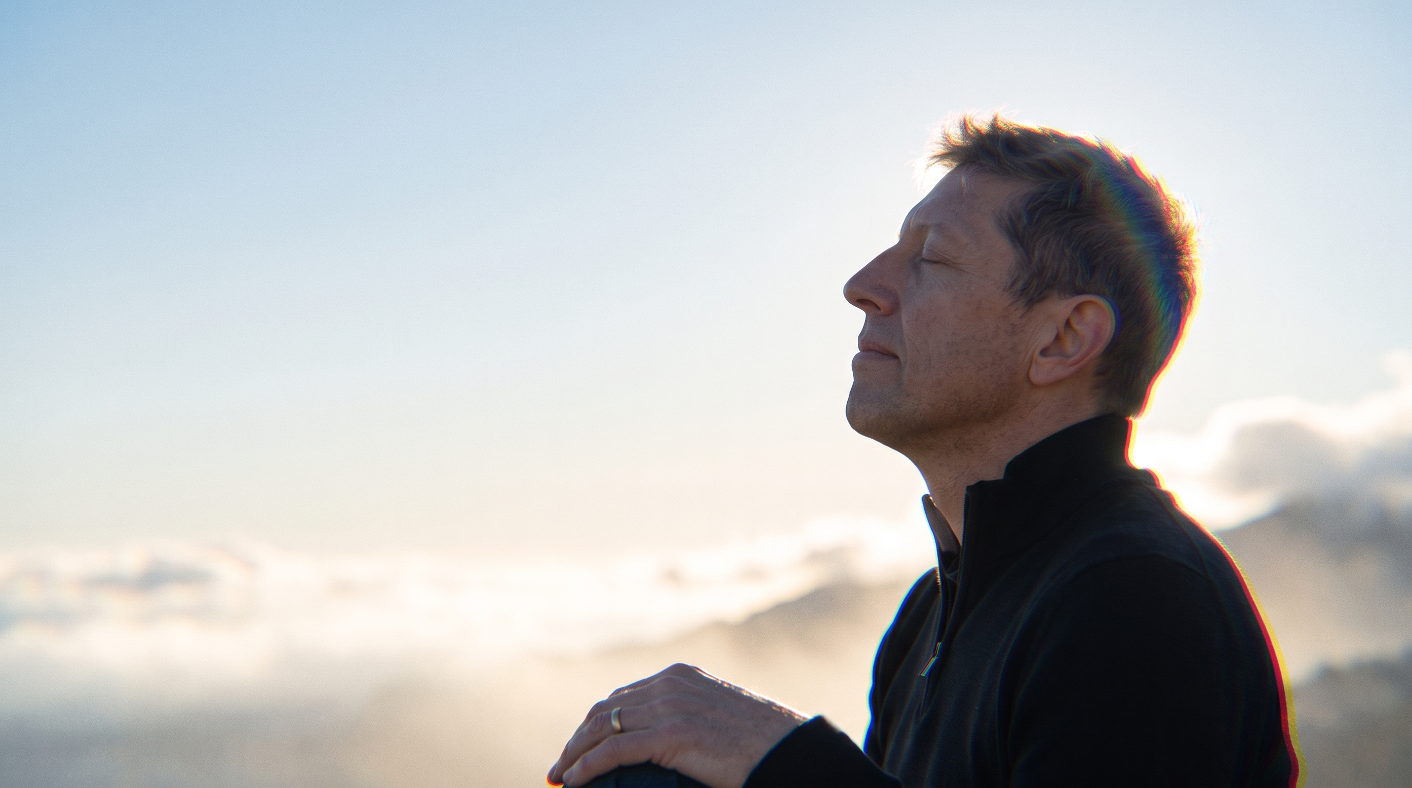 Jesse outdoors at altitude, eyes closed, the light low behind him.